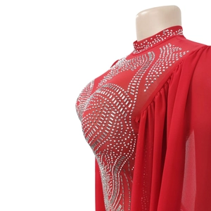 Detailed view of silver rhinestones on red mesh fabric with chiffon sleeves