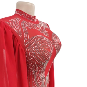 Close-up of red rhinestone jumpsuit with mesh sheer sleeves and sparkling silver gems