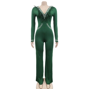 Detail of dark green jumpsuit with deep V-neck, featuring luxury feathers and silver rhinestones