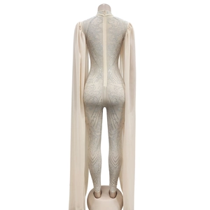 Macro view of cream jumpsuit featuring silver rhinestone patterns and long mesh cape back