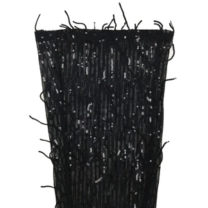 Détail de paillettes noires et franges en maille sur le tissu d'une combinaison
