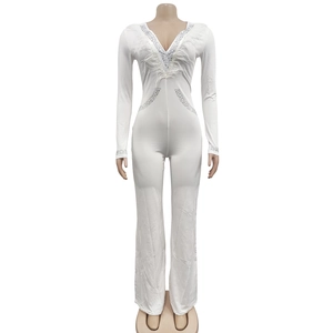 Detail of white deep V-neck jumpsuit featuring sparkling rhinestones and white feather trim