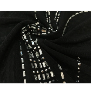 Detail aus schwarzem Netzstoff mit aufwendigen silbernen Strassmustern und Glitzerakzenten