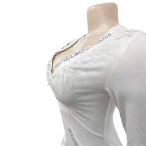 Detailed close-up of white jumpsuit featuring deep V-neck with feathers and rhinestones
