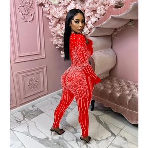 Detailed close-up of red mesh jumpsuit with sparkling rhinestones and elegant feather cuffs