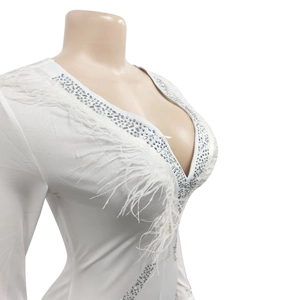 Detail of white deep V-neck jumpsuit with shimmering rhinestones and feather accents