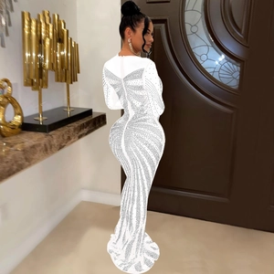 Detail view of a white long-sleeve evening gown with sparkling rhinestones and fishtail hem