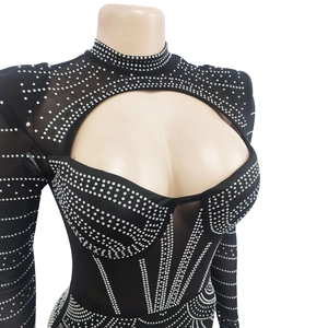 Détail d'une robe de soirée noire avec motifs strass et manches longues en résille