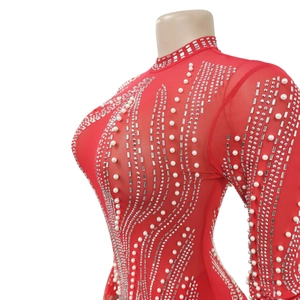 Détail de la robe en tulle rouge ornée de perles blanches et de strass argentés brillants