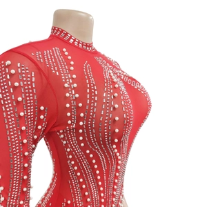 Détail de robe en maille rouge montrant des perles blanches et des strass argentés