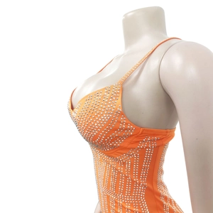 Détail d'une robe tube orange avec strass argentés étincelants et plumes sur un mannequin