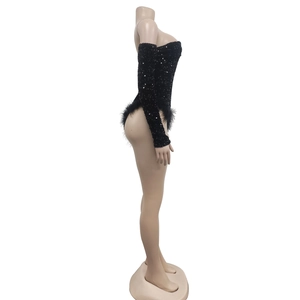 Detail of black sequined bodysuit with long sleeves and ostrich feather trim on the hem