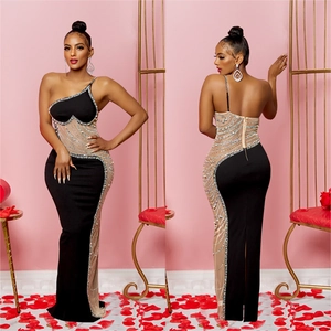 Détail d'une robe maxi noire avec strass, empiècements en résille et coupe asymétrique