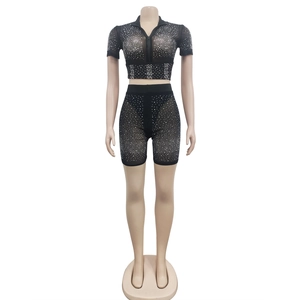 Close-up of sparkling silver rhinestones on black mesh short sleeve top and shorts set