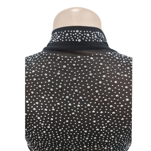Close-up of black sheer mesh fabric with sparkling silver rhinestones on the neckline