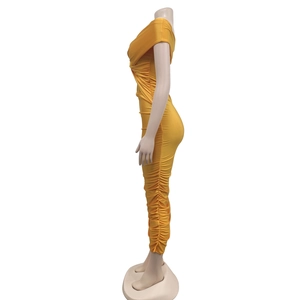 Detail of the side ruching and twisted bust design on a ginger yellow bodycon maxi dress