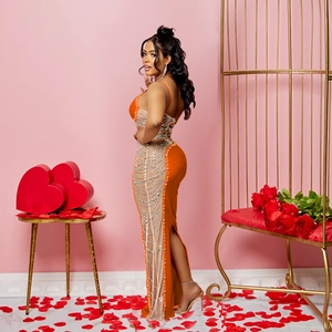 Détail d'une robe de soirée en satin orange avec franges en strass et fente latérale