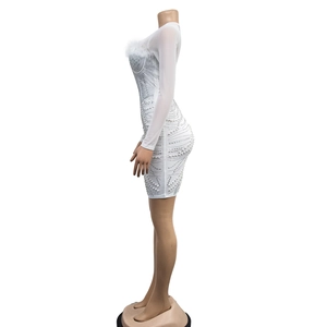 Detail of white mini dress featuring mesh sleeves, faux feathers, pearls, and rhinestones