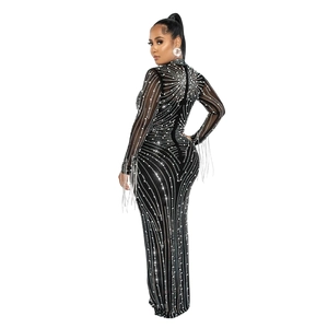 Detailed close-up of rhinestones and long fringe on a black mesh long-sleeve evening dress