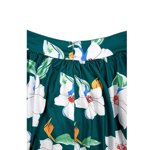 Detailed view of dark green floral dress featuring a hidden zipper and pleated waistline