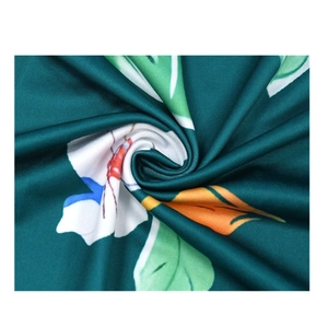 Close-up detail of floral print fabric showing white flowers and orange leaves on dark green