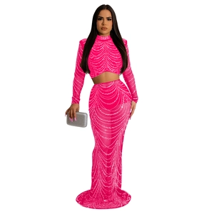 Détail de chaînes de perles argentées sur haut en maille fuchsia et jupe longue maxi