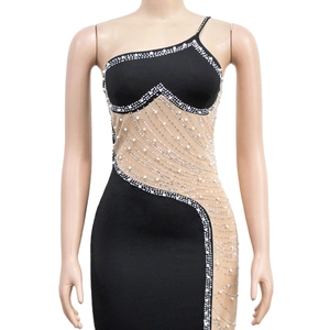 Détail d'une robe de soirée noire à une épaule avec des perles blanches et des strass argentés