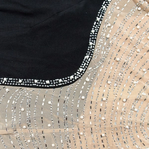 Détail macro des ornements en strass et perles sur la robe de soirée noire