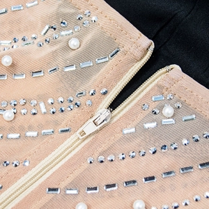 Détail d'une robe de soirée avec strass argentés et perles blanches sur mesh nude