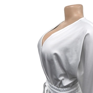 Detail view of white V-neck romper with elastic waist and drawstring cord texture