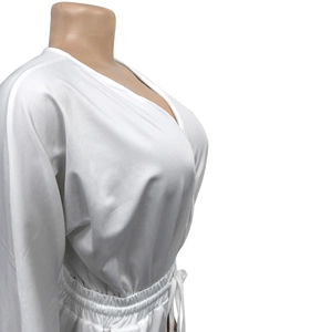 Detail of white V-neck romper featuring an adjustable drawstring waist and long sleeves