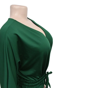 Detail of dark green V-neck romper featuring a drawstring waist and silky satin fabric