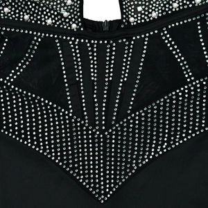 Detail of black mesh jumpsuit featuring intricate rhinestone patterns and pearl neckline trim