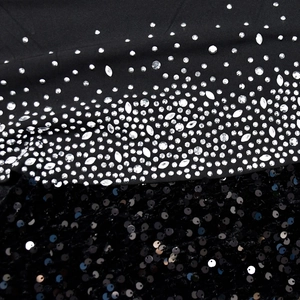 Macro detail of black evening dress fabric featuring silver rhinestones and glossy sequins