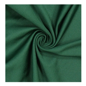 Macro shot of dark green knitted fabric showing fine spiral texture and soft material