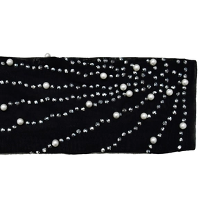 Dettaglio di manica in rete nera con strass argentati e decorazioni di perle bianche