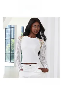 Detail of white ribbed knit top with floral embroidery and elegant sheer lace sleeves