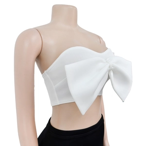 Detail of white tube top featuring a large 3D bow decoration on structured fabric