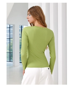 Close-up of grass green ribbed knit fabric and delicate lace trim on the shoulder