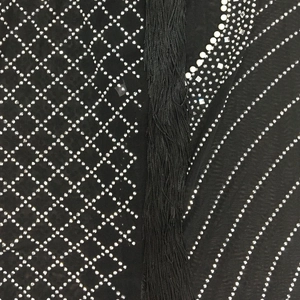 Detail of black mesh dress featuring silver rhinestones in diamond pattern and long tassels