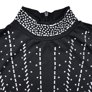 Dettaglio del collo alto con strass argentati e zip posteriore sull'abito nero