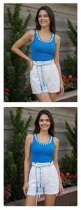 Detail of blue sleeveless top with shell embellishments and white cotton shorts with rope belt