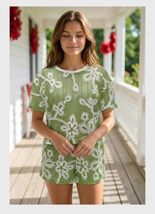 Dettaglio del set in maglia verde con pantaloncini, bordini bianchi e fiori
