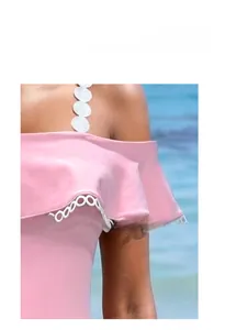 Dettaglio del costume rosa con maniche a volant e bordo in pizzo bianco sulla spiaggia