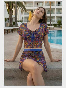 Detail of sunflower print short sleeve crop top and matching mini skirt on pool background