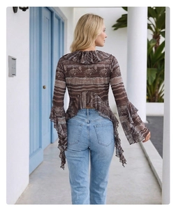 Rear view of long sleeve blouse with elephant print and ruffled hem against a white wall