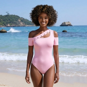 Pink one-shoulder swimsuit with cutout detail and metal eyelets on a beach backdrop