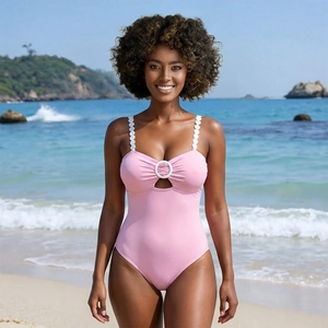 Pink one-piece swimsuit with scalloped straps and ring cutout on sunny beach