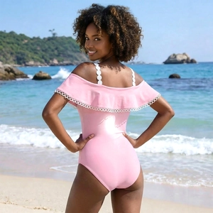 Costume da bagno intero rosa con spalline in pizzo e volant sulla spiaggia