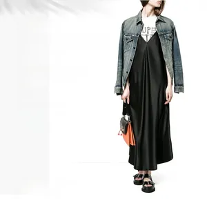 Détail d'une robe nuisette en satin noir avec une veste en jean bleu clair délavé